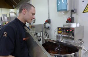 Du chocolat, de la fève à la tablette Mathieu Robin devant in moulin où nait le chocolat après des heures de broyage