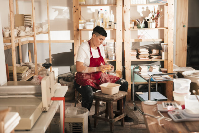 young-female-potter-cleaning-ceramic-tiles-workshop